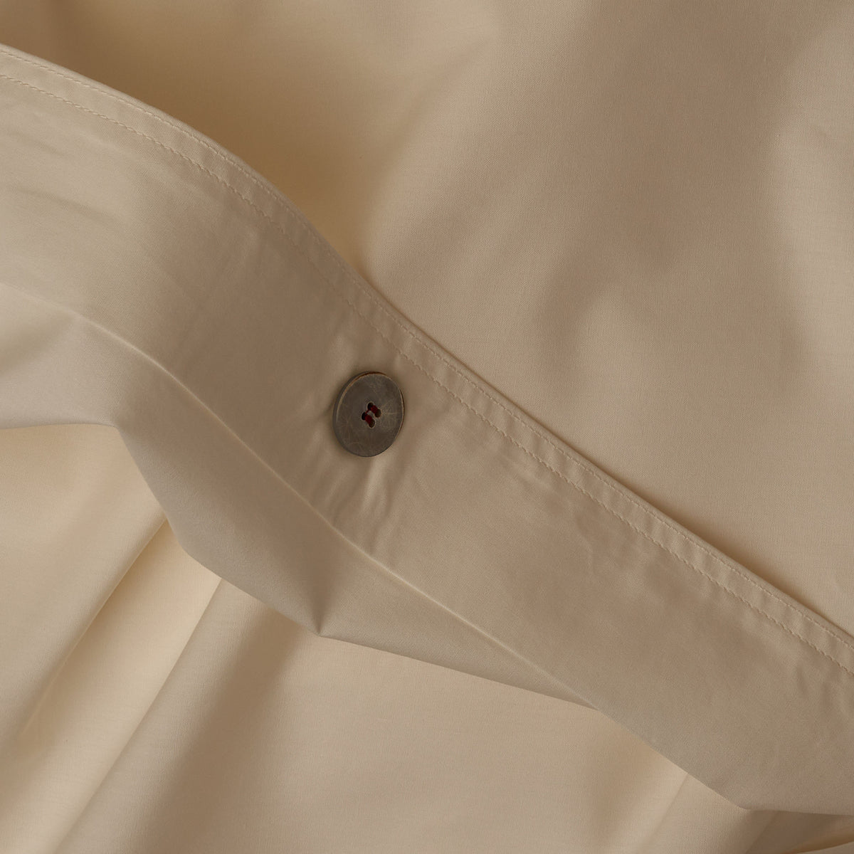 Close up image of the button closure on a LETTO Classic Cotton Percale duvet cover in color ivory. data-image-id=