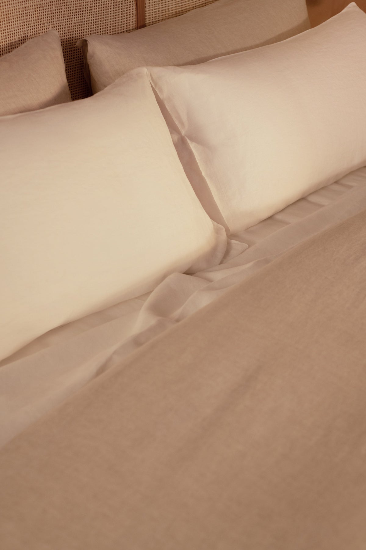 A close up image of a bed made with white Classic Linen sheets and a Classic Linen duvet cover in color Natural. data-image-id=