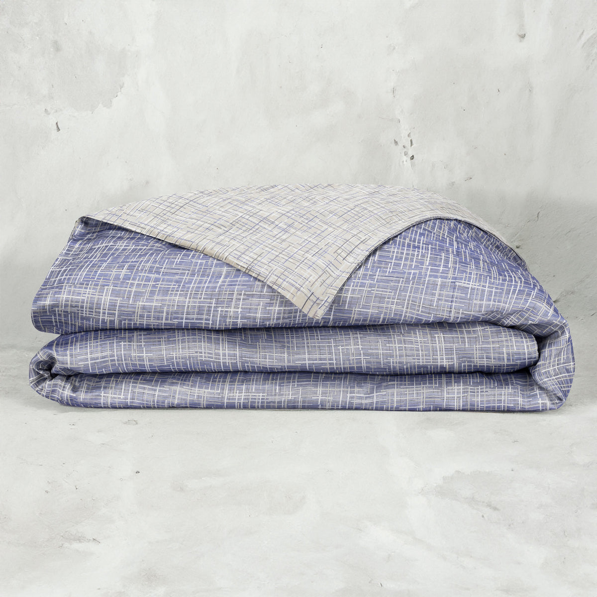 A folded LETTO Mosaico Jacquard Duvet cover in color Denim.  data-image-id=