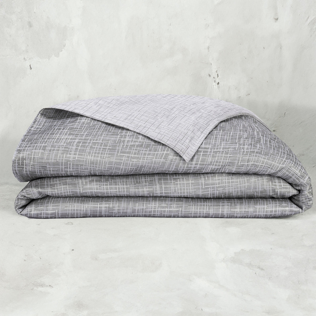 A folded LETTO Mosaico Jacquard Duvet cover in color Heather. data-image-id=