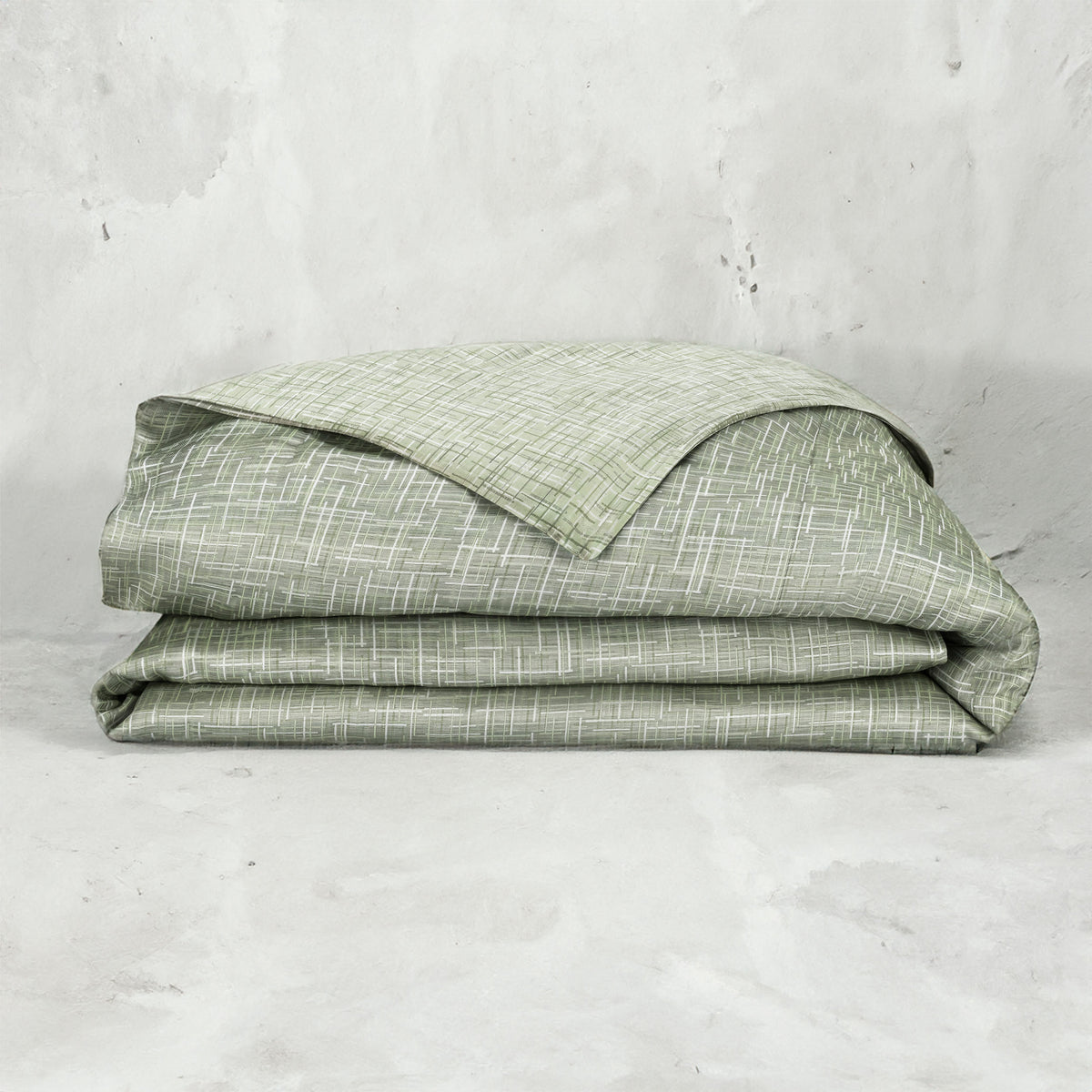 A folded LETTO Mosaico Jacquard Duvet cover in color Moss.  data-image-id=