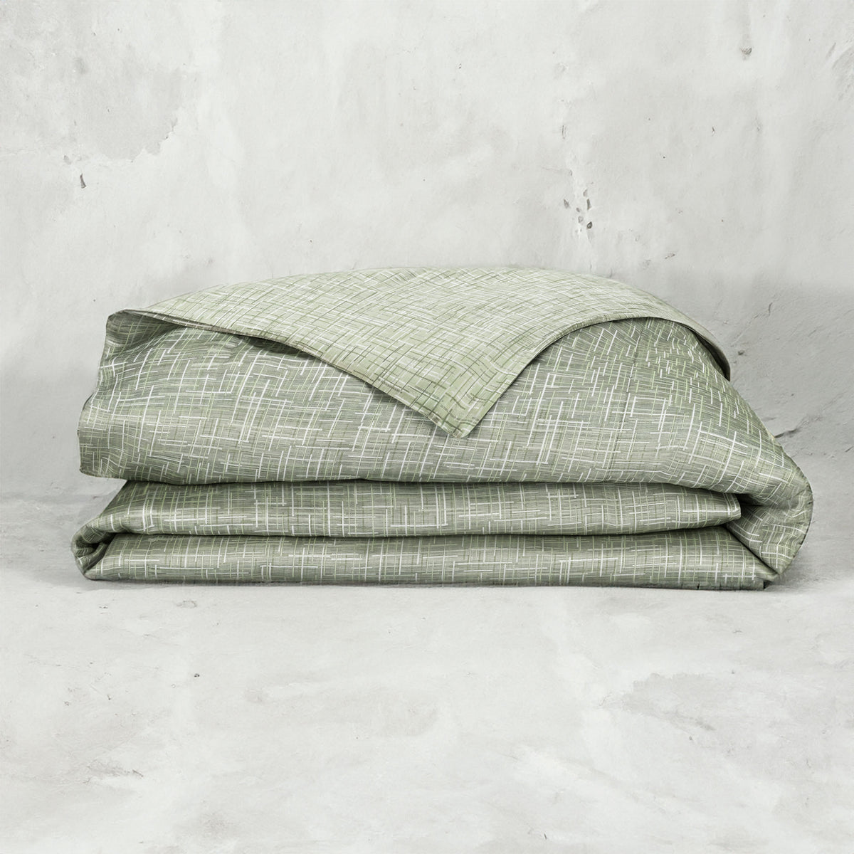 A folded LETTO Mosaico Jacquard Duvet cover in color Moss. data-image-id=