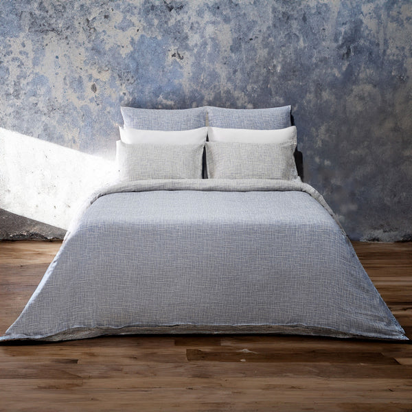 A bed made with the LETTO Mosaico Jacquard Duvet and Sham set in color Denim.