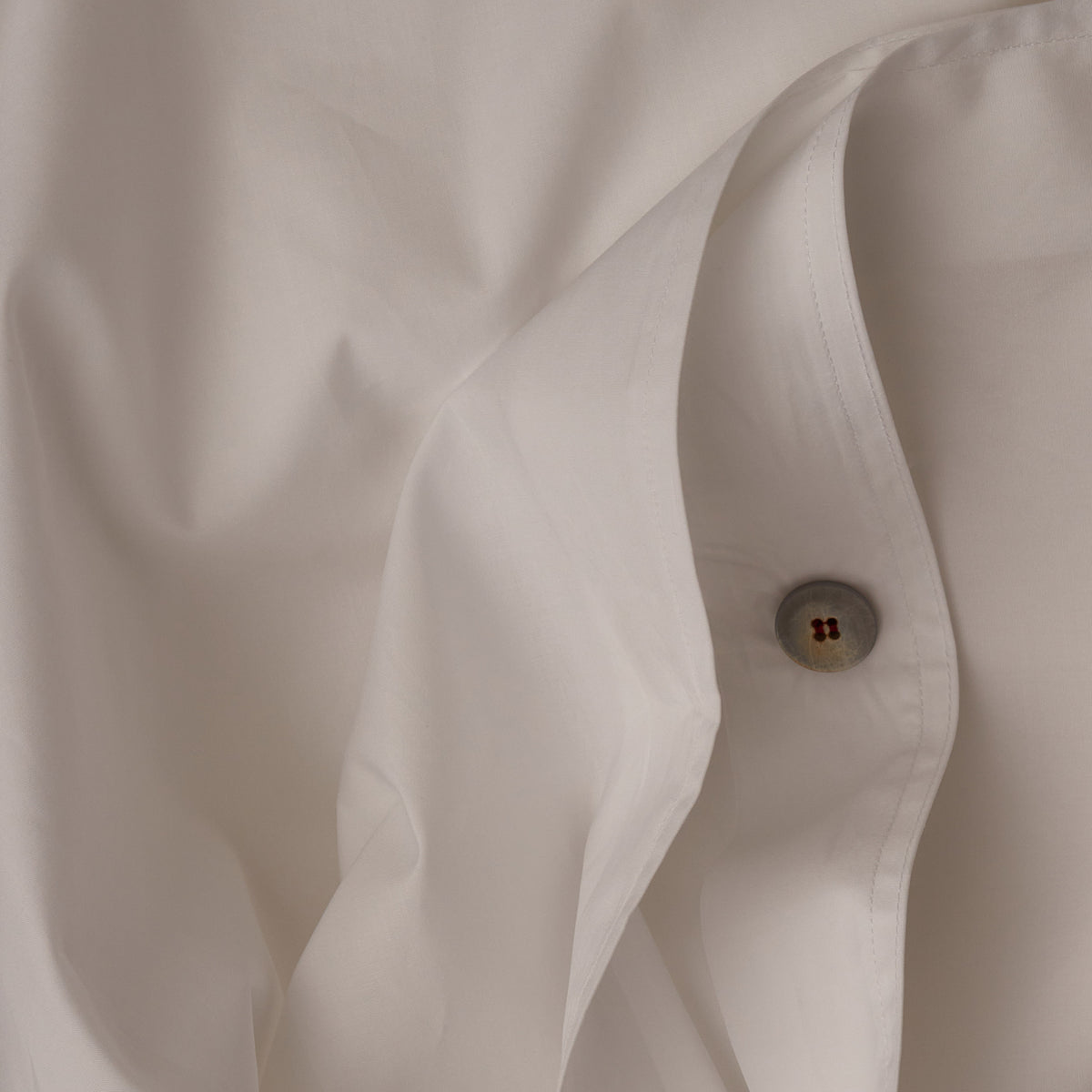 Close up image of the button closure on a LETTO Giza Reserve Cotton Percale crisp and cool duvet cover in color white. data-image-id=