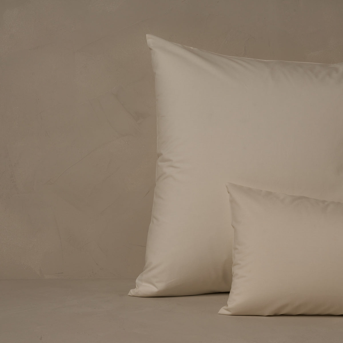 An image of a small boudoir or travel size pillow stacked in front of a large euro size pillow. The pillow cases are made of LETTO's crisp and cool Classic Cotton Percale in color ivory. data-image-id=