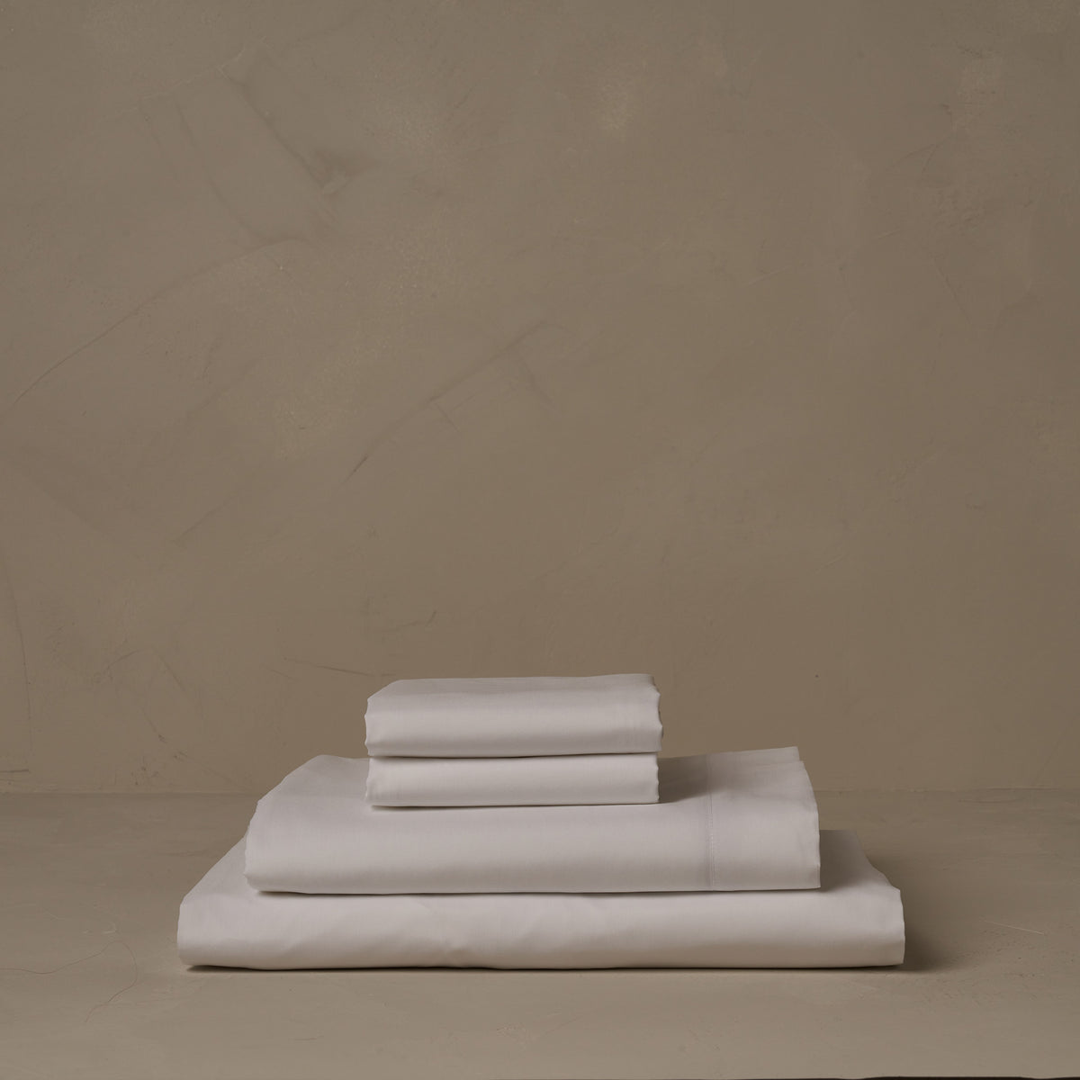A stack of crisp and cool LETTO Classic Cotton Percale sheets in color white, made in Italy. The sheet set includes a fitted sheet, a flat sheet, and a pair of pillowcases. data-image-id=