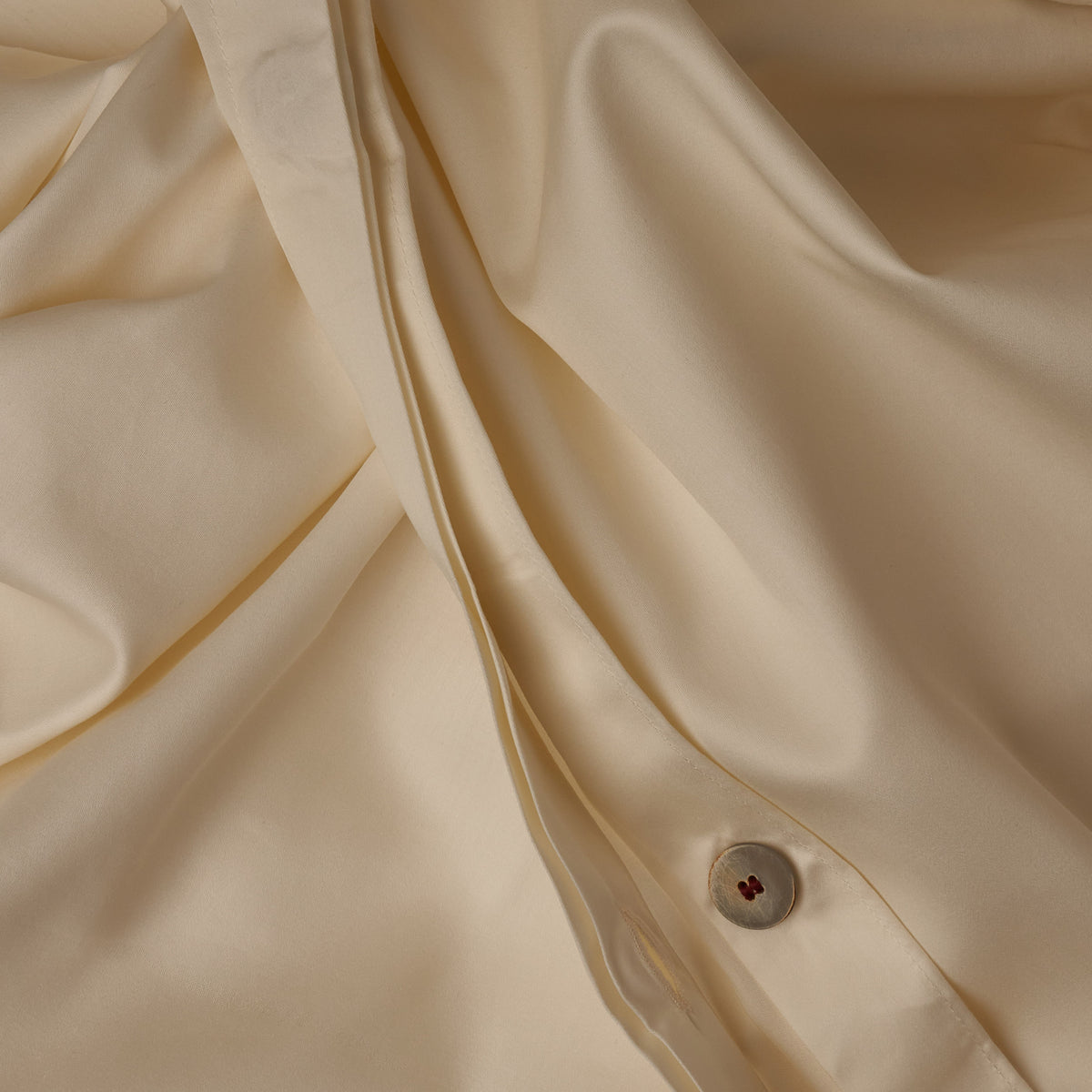 Close up image of the button closure on a LETTO Classic Cotton Sateen duvet cover in color ivory. data-image-id=