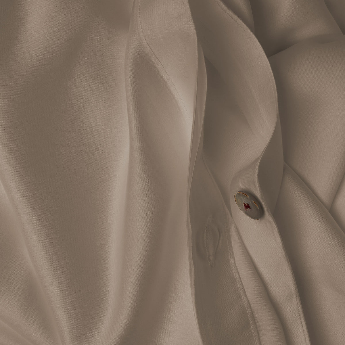 Close up image of the button closure on a LETTO Woodland Silk soft and silky duvet cover in color candlelight. data-image-id=