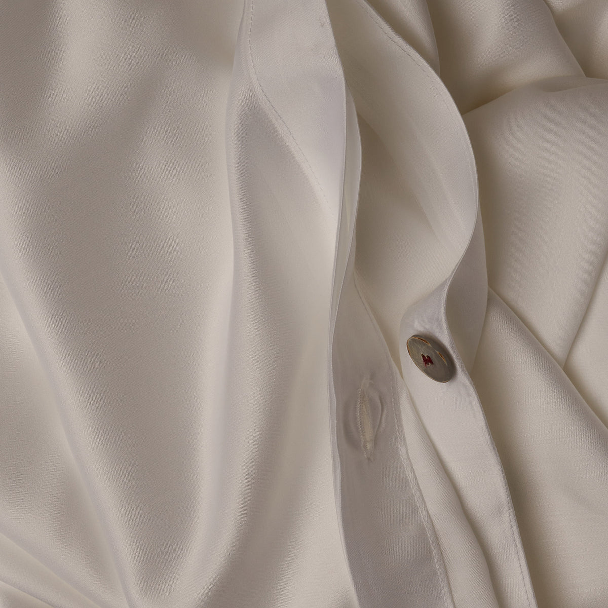 Close up image of the button closure on a LETTO Woodland Silk soft and silky duvet cover in color white. data-image-id=