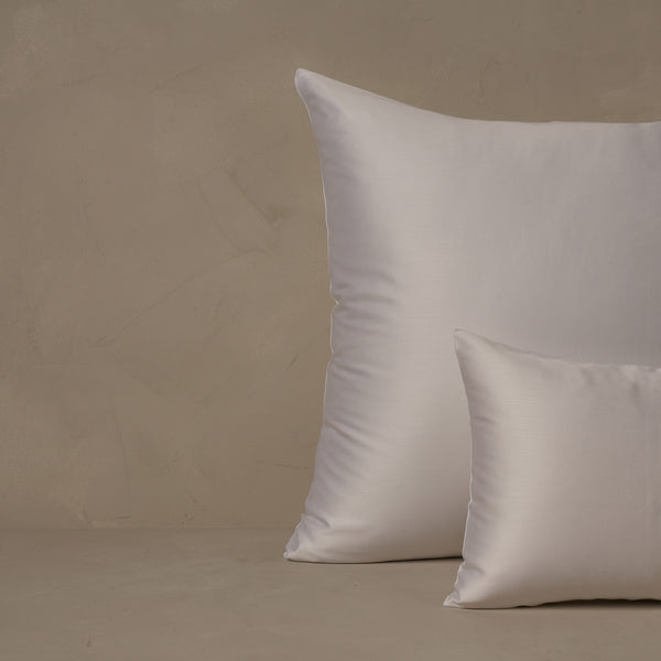 An image of a small boudoir or travel size pillow stacked in front of a large euro size pillow. The pillow cases are made in Italy of LETTO Woodland Silk fabric in color white, a smooth and silky beechwood modal.
