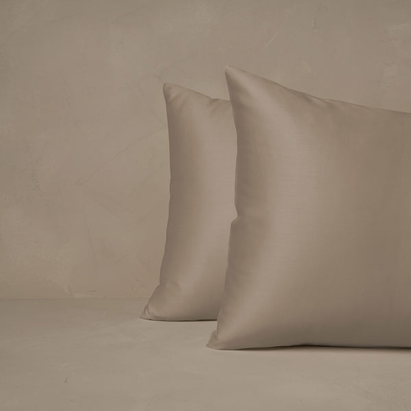 An image of two pillows stacked one in front of the other. The pillow cases are made of LETTO Woodland Silk beechwood modal in color candlelight.