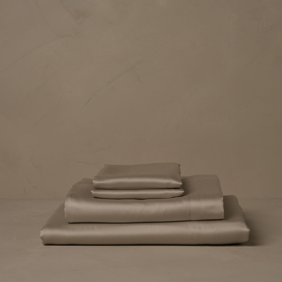 A stack of smooth and silky LETTO Woodland Silk beechwood modal sheets in candlelight, made in Italy. The sheet set includes a fitted sheet, a flat sheet, and a pair of pillowcases. data-image-id=