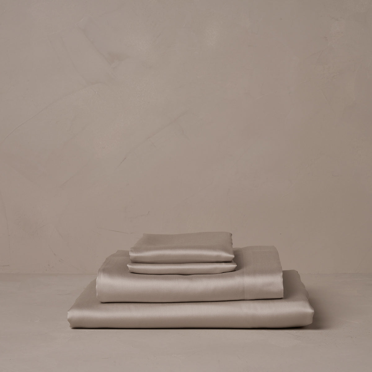A stack of smooth and silky LETTO Woodland Silk beechwood modal sheets in gray, made in Italy. The sheet set includes a fitted sheet, a flat sheet, and a pair of pillowcases. data-image-id=