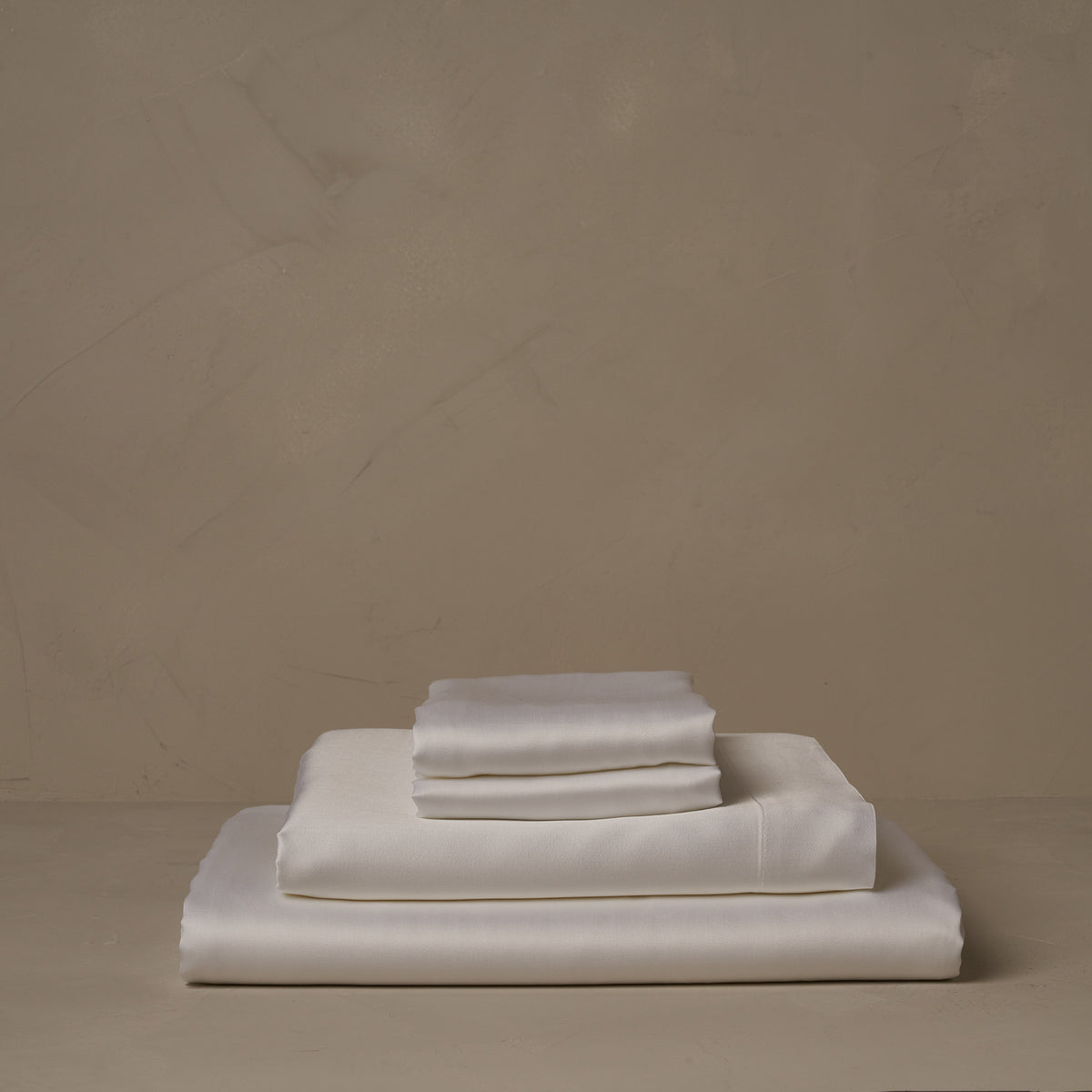 A stack of smooth and silky LETTO Woodland Silk beechwood modal sheets in white, made in Italy. The sheet set includes a fitted sheet, a flat sheet, and a pair of pillowcases. data-image-id=