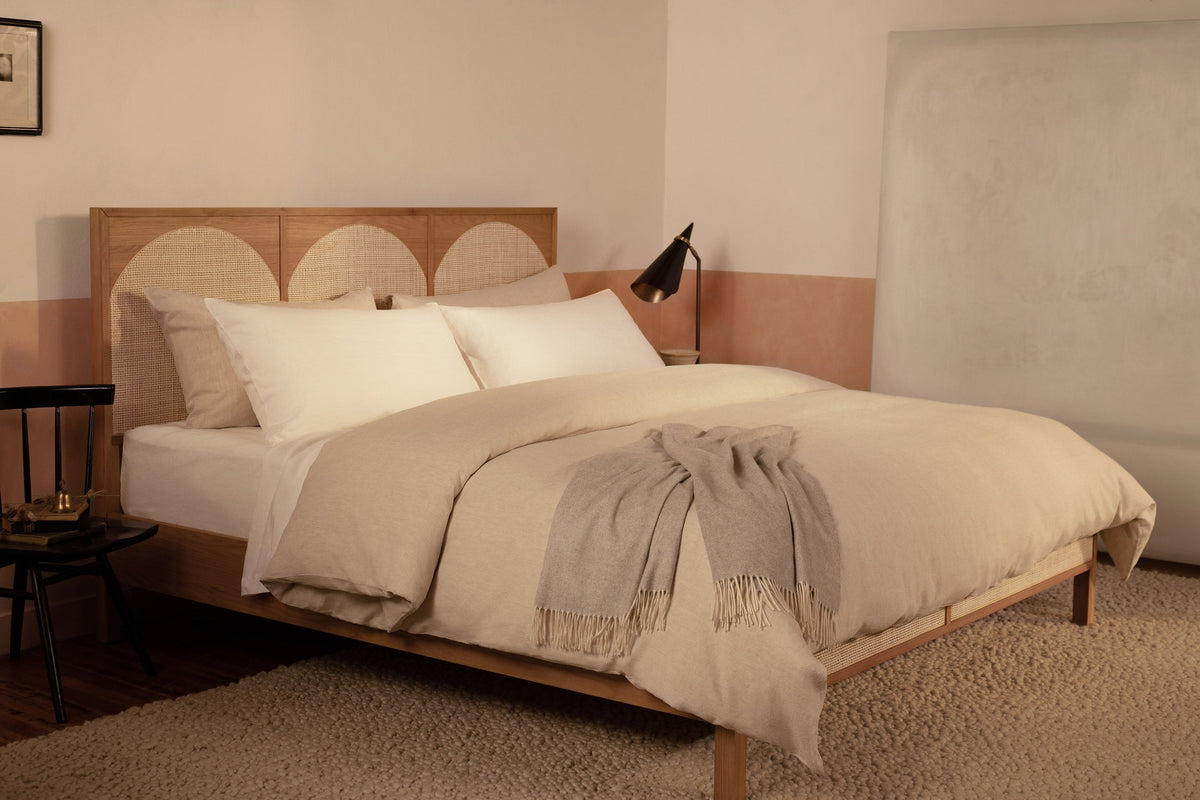 A contemporary bed made with white Classic Linen sheets and a Classic Linen duvet cover in color Natural. The sheets are made of Belgian linen and woven in Italy. The bed has a light gray Coccola cashmere throw blanket draped at the foot of the bed. data-image-id=