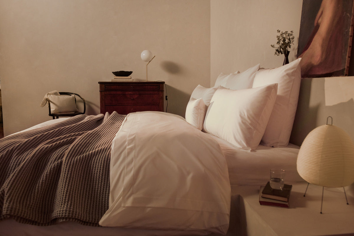 A bedroom with a luxuriously made bed in LETTO Giza Reserve Cotton Percale sheets and duvet cover in color white, with a gray Nido waffleweave cotton blanket. data-image-id=