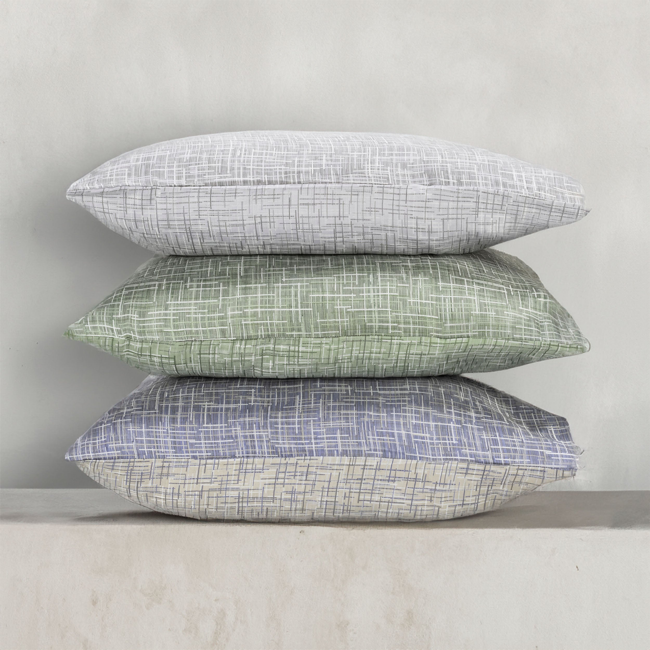 A stack of pillows in three colors of the with LETTO Mosaico Jacquard pattern.