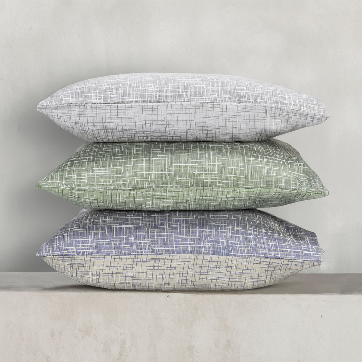A stack of pillows in three colors of the with LETTO Mosaico Jacquard pattern. data-image-id=