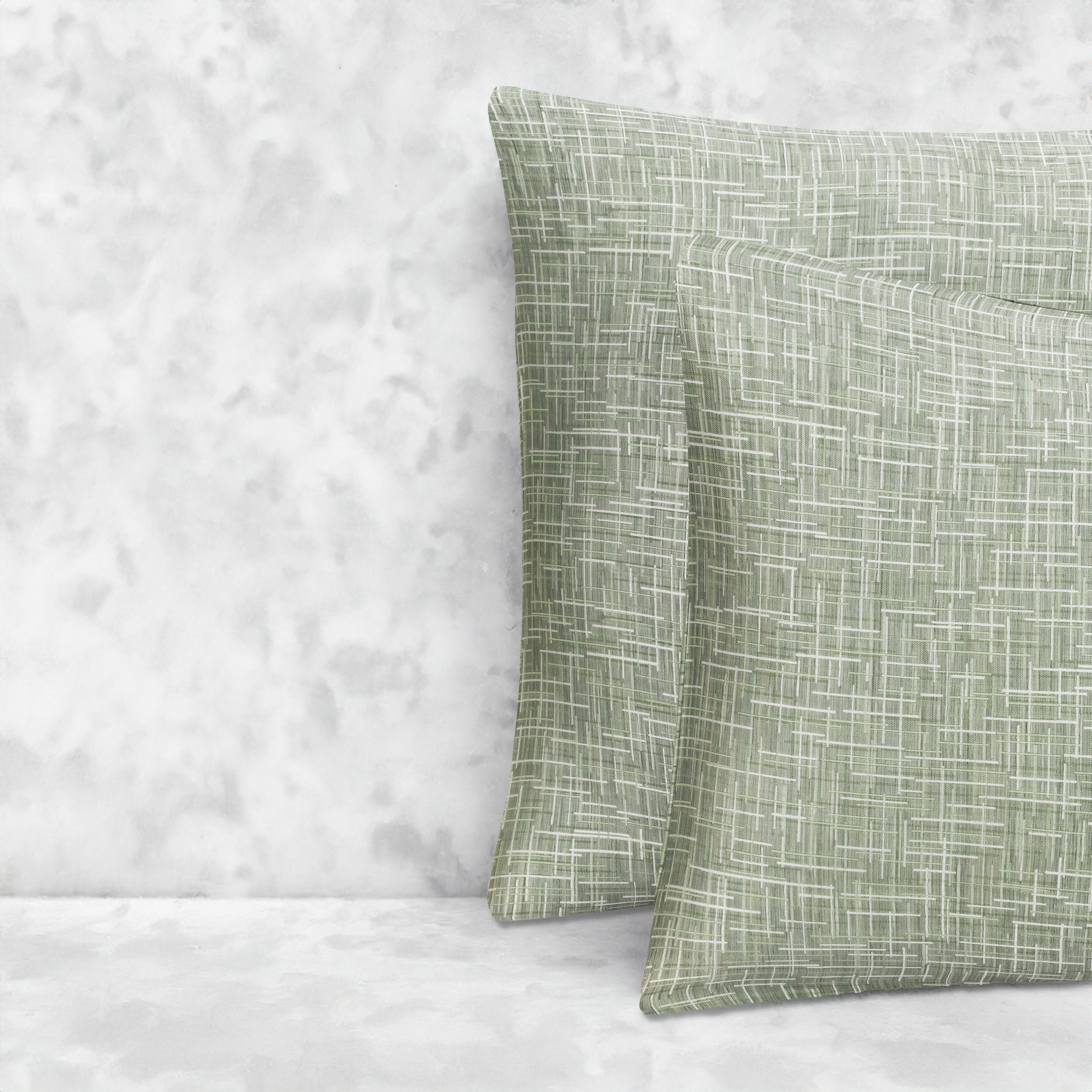 An image of two pillows stacked one in front of the other. The pillow cases are made of LETTO Mosaico Jacquard fabric in color Green.