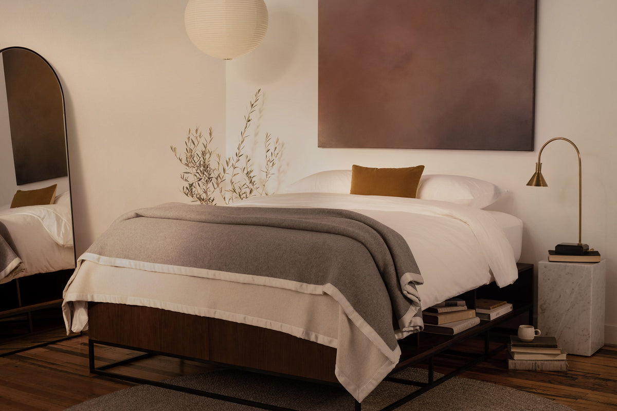 A bedroom with contemporary art and a platform bed made in LETTO 100% Organic Cotton Percale sheets, a gray Monte Bianco cashmere blanket, and orange velvet throw pillow. data-image-id=