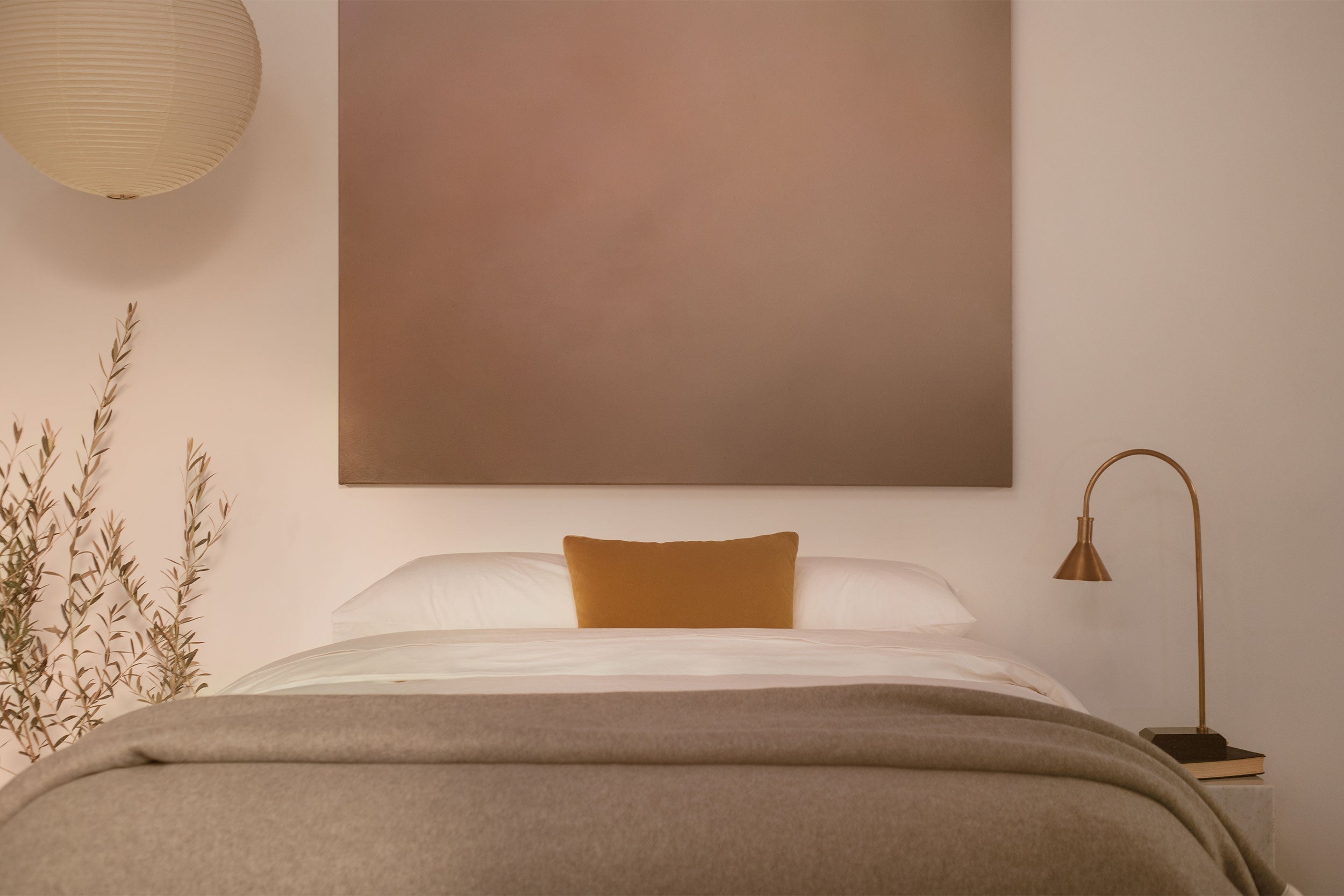 A bedroom with contemporary art and a platform bed made in LETTO 100% Organic Cotton Percale sheets, a gray Monte Bianco cashmere blanket, and orange velvet throw pillow.