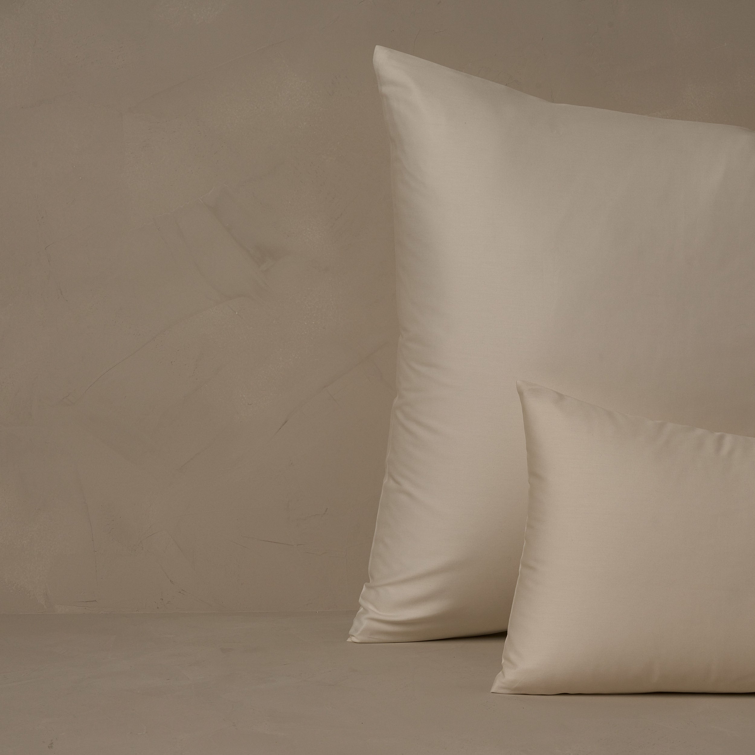 An image of a small boudoir or travel size pillow stacked in front of a large euro size pillow. The pillow cases are made of LETTO's warm and buttery Classic Cotton Sateen in color ivory.