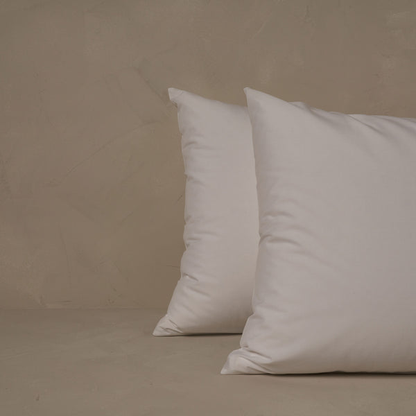 An image of two pillows stacked one in front of the other. The pillow cases are made of LETTO Americano Cotton Percale in color white.