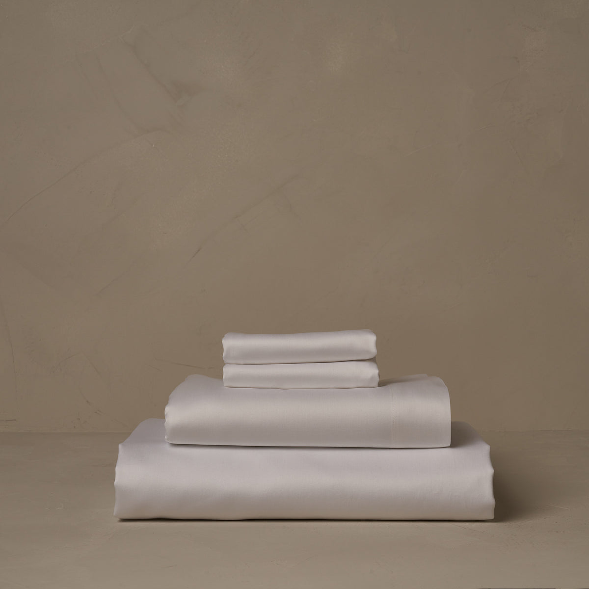 A stack of warm and buttery LETTO Americano Cotton Sateen sheets in white, made in Italy of American grown Supima Cotton. The sheet set includes a fitted sheet, a flat sheet, and a pair of pillowcases. data-image-id=
