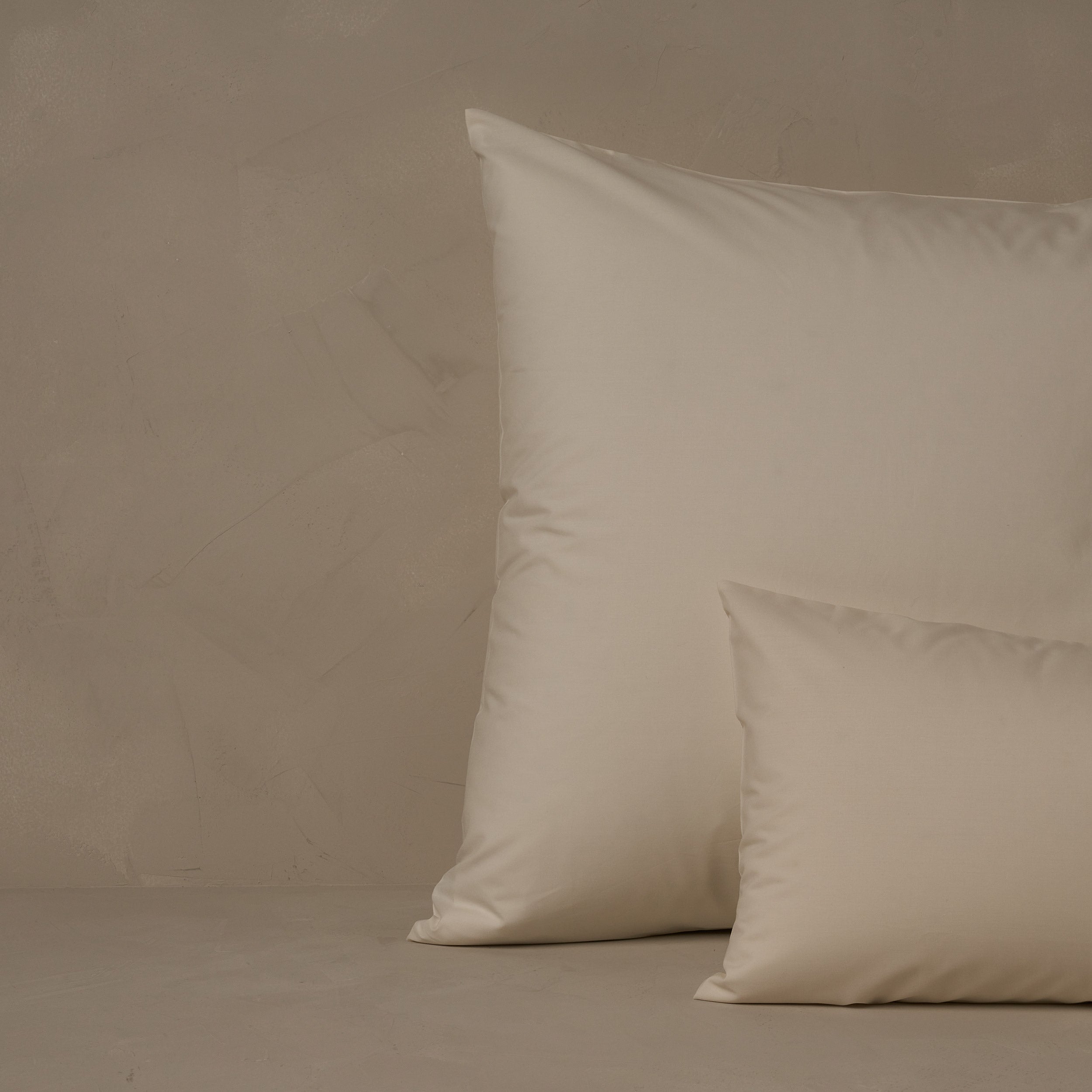 An image of a small boudoir or travel size pillow stacked in front of a large euro size pillow. The pillow cases are made of LETTO's crisp and cool Classic Cotton Percale in color ivory.