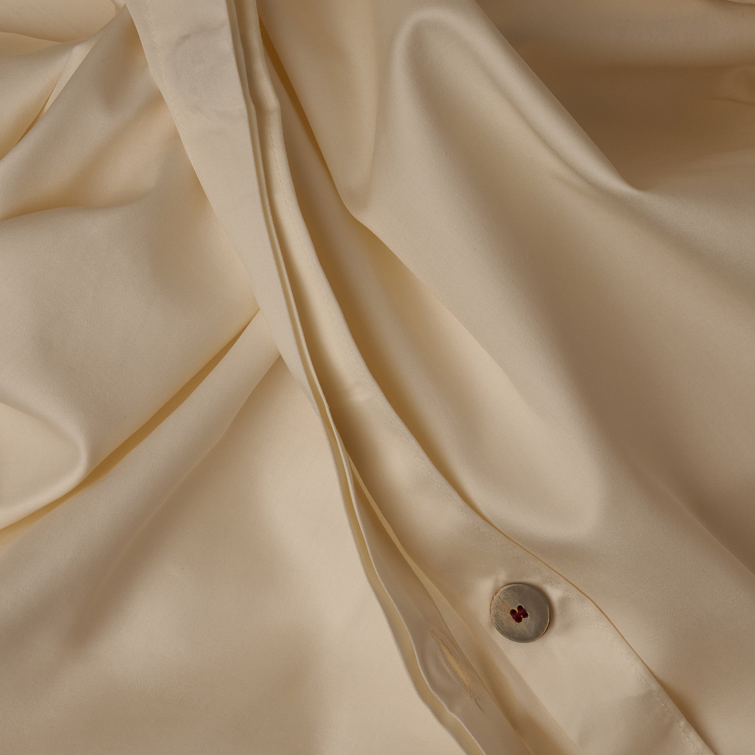 Close up image of the button closure on a LETTO Classic Cotton Sateen duvet cover in color ivory.