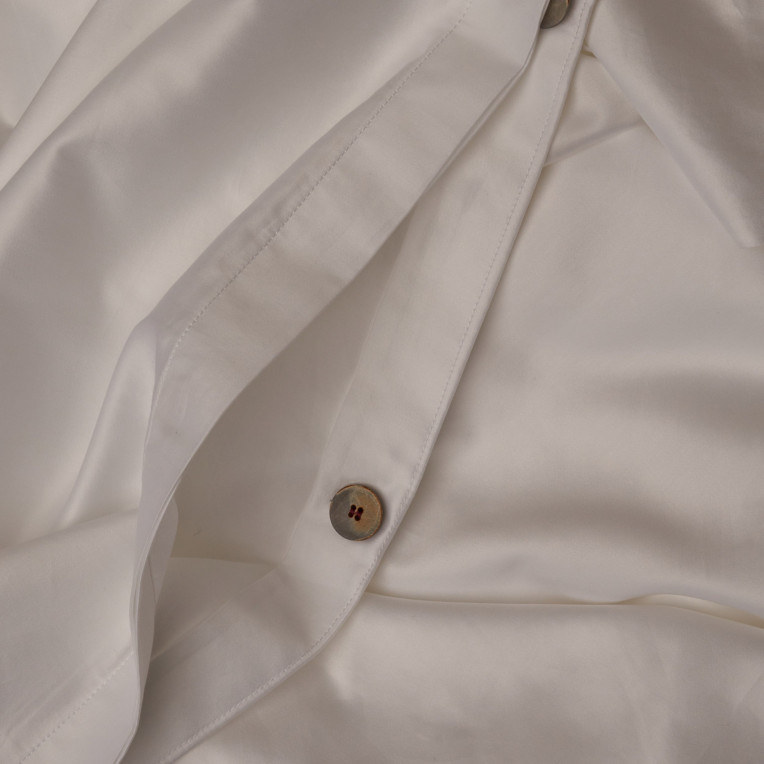 Close up image of the button closure on a LETTO Classic Cotton Sateen duvet cover in color white.