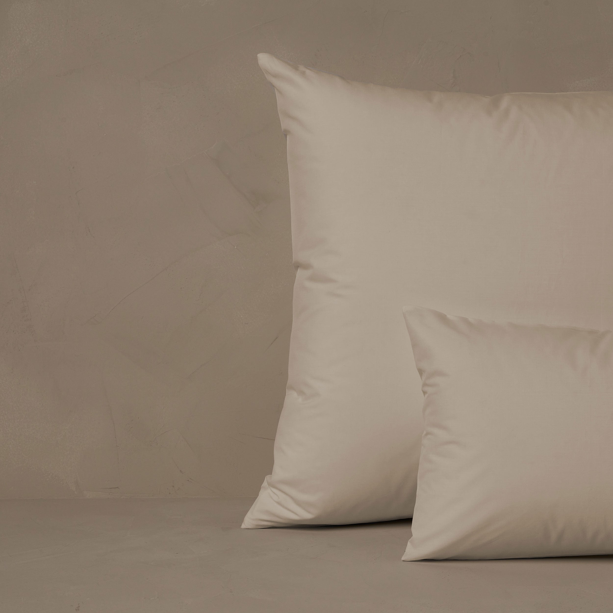 An image of a small boudoir or travel size pillow stacked in front of a large euro size pillow. The pillow cases are made in Italy of crisp and cool LETTO Giza Reserve Cotton Percale in color ivory.