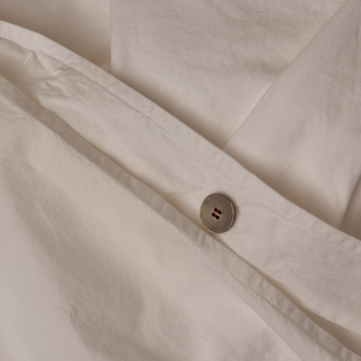 Close up image of the button closure on a LETTO 100% Organico Cotton Percale crisp and cool duvet cover in color white. data-image-id=