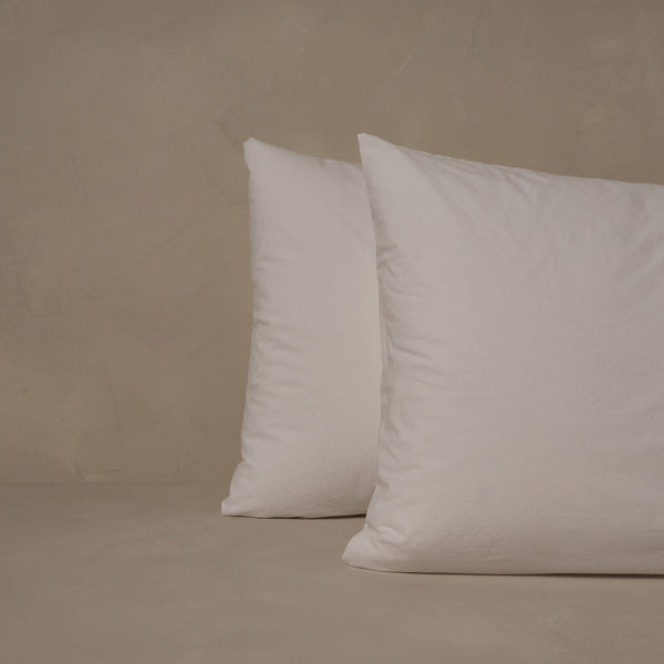 An image of two pillows stacked one in front of the other. The pillow cases are made of LETTO 100% Organic Cotton Percale in color white.