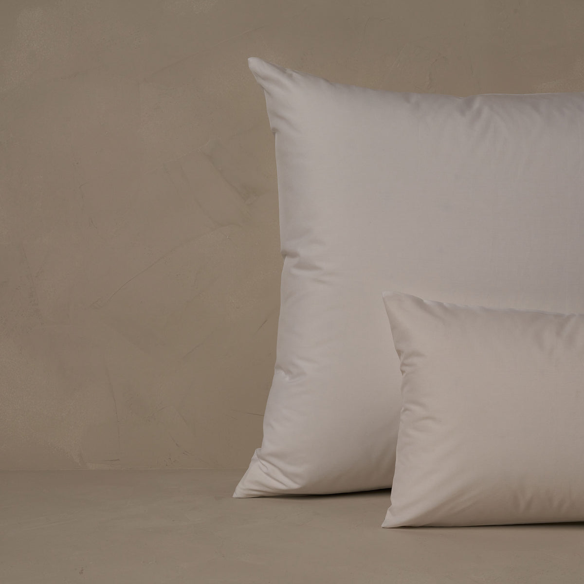 An image of a small boudoir or travel size pillow stacked in front of a large euro size pillow. The pillow cases are made in Italy of ultra soft and cool Sea Island Cotton Percale in color white. data-image-id=