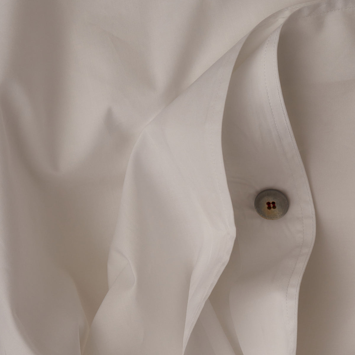 Close up image of the button closure on a LETTO Sea Island Cotton Percale ultra soft and cool duvet cover in color white. data-image-id=