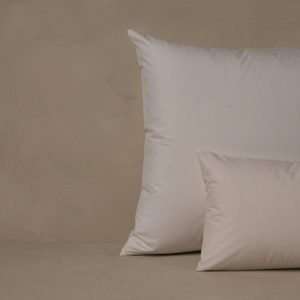 An image of a small boudoir or travel size pillow stacked in front of a large euro size pillow. The pillow cases are made in Italy of ultra soft and cool Sea Island Cotton Percale in color white.