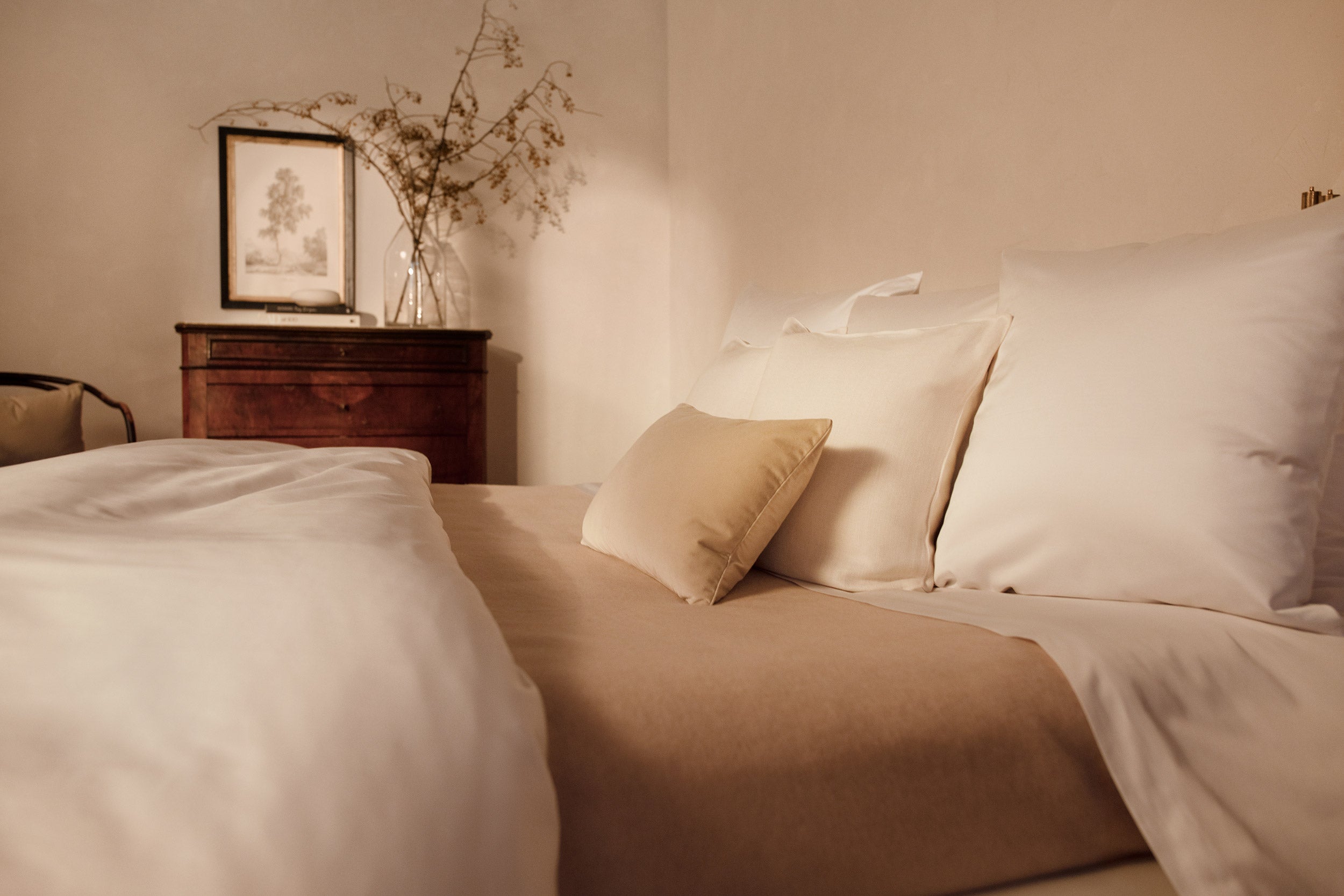A close up image of LETTO Sea Island Cotton Sateen pillows in white on a bed with a cream colored Monte Bianco cashmere blanket.