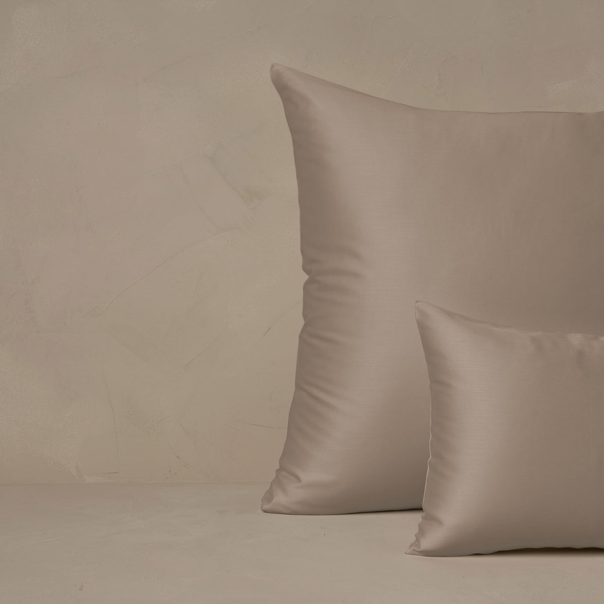 An image of a small boudoir or travel size pillow stacked in front of a large euro size pillow. The pillow cases are made in Italy of LETTO Woodland Silk fabric in color Candlelight, a smooth and silky beechwood modal. data-image-id=